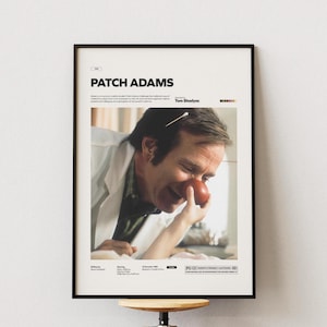 Può includere: Un poster cinematografico incorniciato per "Patch Adams" con un primo piano di un uomo con un naso rosso da clown. Il poster ha una cornice nera e include il titolo e i crediti del film.