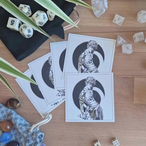 Könnte beinhalten: Eine Auswahl an Tabletop-Gaming-Zubehör auf einer Holzoberfläche. Enthält Würfel, Karten mit einer Illustration einer Figur vor einem Halbmond, Kristalle und einen kleinen Beutel mit Edelsteinen.