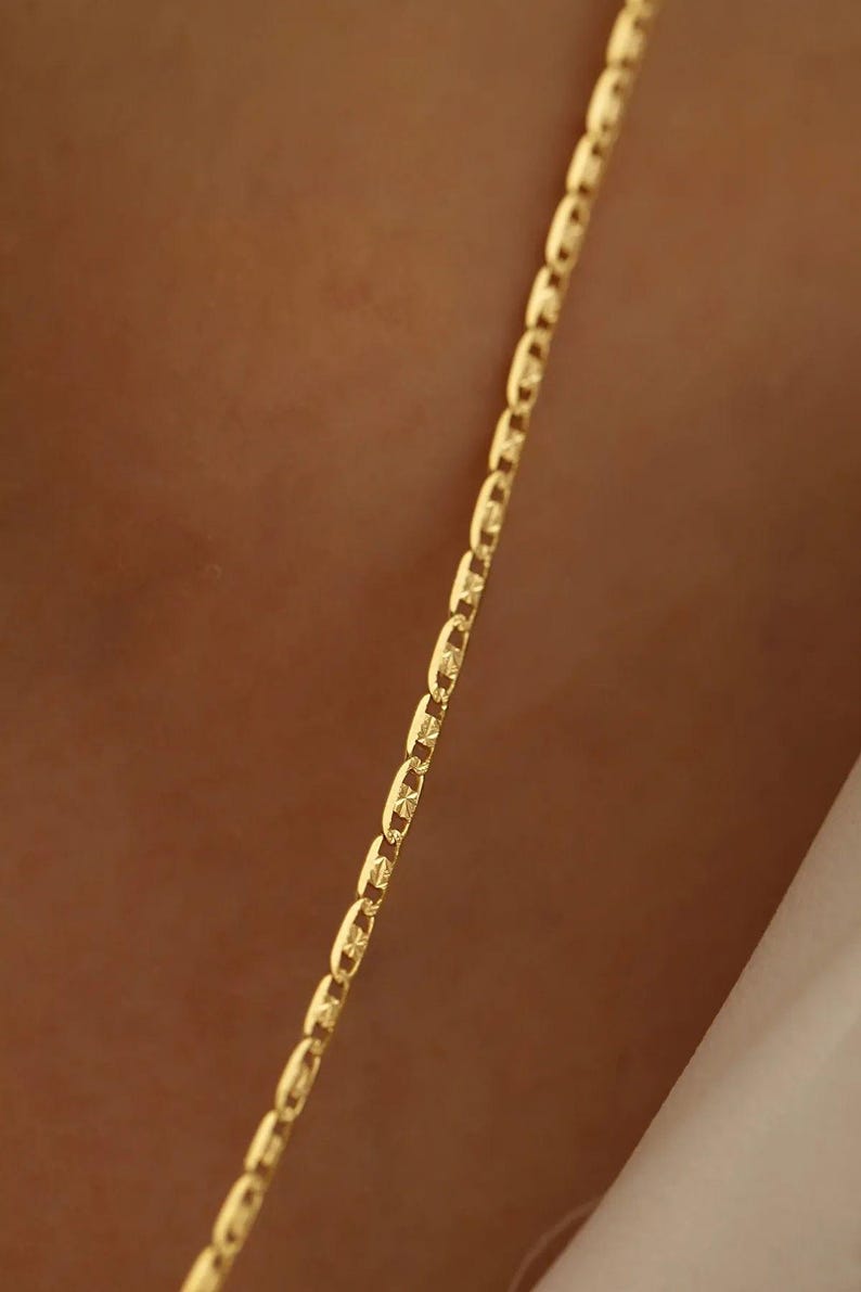 May include: A gold chain necklace with a mariner link style. The chain is made of solid gold and has a polished finish.