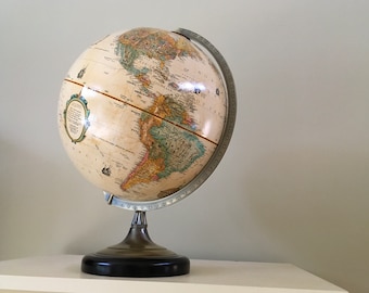 May include: A vintage-style globe with a cream-colored map and a brass stand. The globe is tilted to show the Americas.