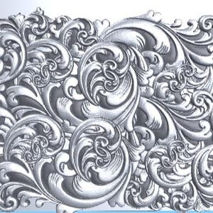 Puede incluir: Un panel rectangular de tono plateado con un patrón de relieve denso y repetitivo de intrincadas hojas de acanto y volutas ornamentadas. La superficie muestra reflejos de alto contraste y sombras profundas que enfatizan la profundidad tridimensional.