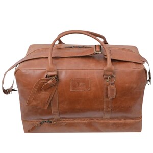 May include: A brown leather duffel bag with a top handle, shoulder strap, and a luggage tag. The bag has a rectangular shape with a zipper closure and a small embossed logo. The leather has a distressed look.