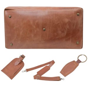 May include: A brown leather duffel bag with brass-colored rivets and hardware. Includes a matching luggage tag, shoulder strap, and key ring tag. The bag is rectangular with rounded corners, and the accessories are also brown leather.