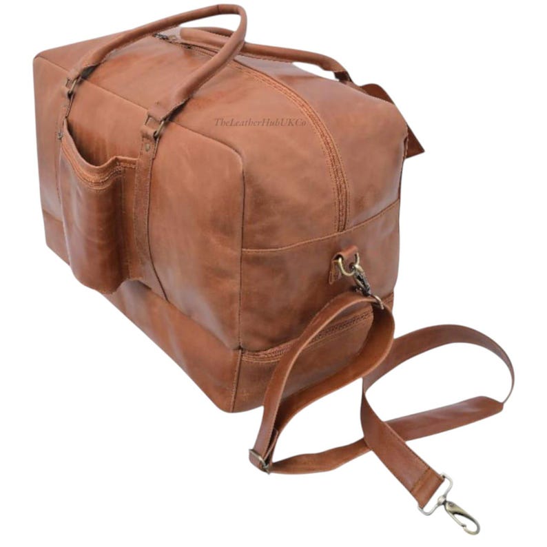 Side view of spacious tan leather duffle bag with detachable strap and separate shoe compartment