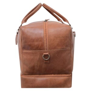 Side view of genuine tan leather duffle bag showing spacious design and detachable strap