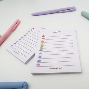 May include: Two to-do list notepad sets with rainbow cloud designs. Each set has a different colour scheme. The text on the notepad says "to do list" and "have a rainbow day!"