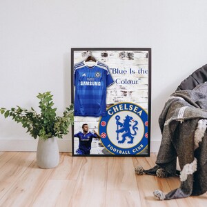 May include: A framed print featuring a blue Chelsea Football Club jersey with the Samsung logo, a white brick background, and the text "Blue is the Colour" and the Chelsea Football Club logo with a lion.