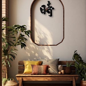 May include: A black wall clock with Chinese characters for "time" in a modern, minimalist style. The clock is hanging on a wall with a wooden archway. The clock is in a room with a wooden bench, pillows, and plants.
