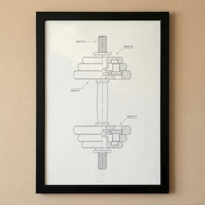 Puede incluir: Impresión enmarcada en negro que muestra un dibujo técnico detallado de una mancuerna. El diagrama en blanco y negro incluye etiquetas como "UNIT-01" y "MOD-07". La obra de arte está montada sobre un fondo blanco.