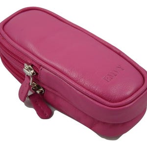 Puede incluir: Una bolsa de cuero rosa con cremallera y la palabra "EMVY" grabada en la parte delantera.