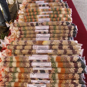 May include: A variety of dried beans and lentils packaged in clear plastic bags. The bags are stacked on top of each other and labeled with different flavors, including "Chicken Tomato Flavored" and "Bean Soup".