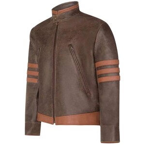 Puede incluir: Chaqueta de cuero marrón con cuello alzado y cremallera. La chaqueta presenta dos bolsillos diagonales con cremallera y tres rayas marrones en cada manga. El cuello y los puños tienen un ribete marrón claro.