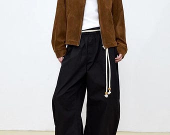 May include: A brown suede jacket with a zipper closure and a white drawstring belt. The jacket has a collar and is decorated with small metal studs.