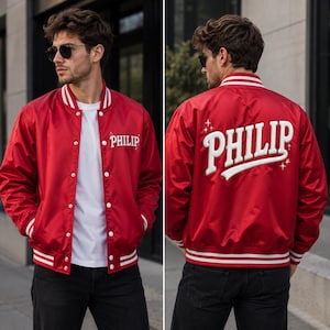 May include: A red varsity jacket with white striped ribbed trim on the collar, cuffs, and hem. The front features the name PHILIP in white embroidery. The back displays the name PHILIP in large white lettering with small star accents.