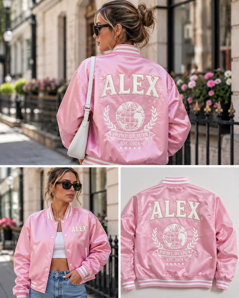 May include: A light pink satin bomber jacket featuring white striped ribbed trim at the collar, cuffs, and hem. The back displays white embroidered text reading ALEX, a globe graphic, and the words PRINT DESIGN EST. 2024 with five small stars.