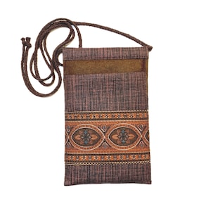 May include: A rectangular brown crossbody bag with a woven texture and a decorative band of orange, blue, and brown floral patterns. The bag has a brown suede panel and a long, braided strap.