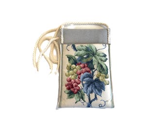 May include: A rectangular fabric pouch featuring a cream-colored panel with a printed design of green and red grapes with blue and green leaves. The upper section is solid gray fabric, and the pouch includes a thick, cream-colored twisted rope cord.