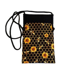 May include: A black and yellow cell phone crossbody bag with a sunflower and bee pattern. The bag features a black top and a black cord strap. The pattern includes yellow sunflowers, bees, and a honeycomb design.