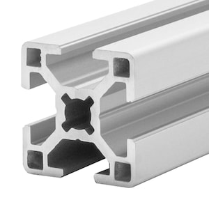 Peut inclure: Gros plan d'un profilé d'extrusion en aluminium argenté. Le profilé a une forme en coupe transversale complexe avec de multiples canaux et un noyau central. Le matériau est de couleur gris clair et semble neuf.