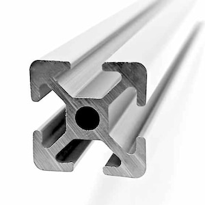 Könnte beinhalten: Nahaufnahme eines silberfarbenen Aluminium-Extrusionsprofils. Das Profil hat einen kreuzförmigen Innenraum mit einem zentralen kreisförmigen Loch. Die Kanten sind abgerundet, und das Gesamtdesign ist industriell.