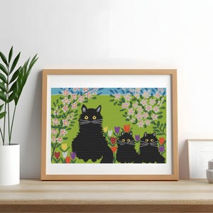 Peut inclure: Une œuvre d'art au point de croix encadrée représentant trois chats noirs dans un jardin. Les chats sont entourés de tulipes colorées et d'arbres en fleurs sur un fond vert. L'œuvre est exposée sur une surface en bois.