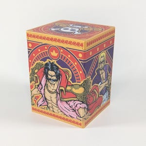 May include: A square, wooden box featuring colorful illustrations of characters from the anime series One Piece. The box has a red, purple, and gold color scheme, with a skull and crossbones design on the top. The box is a collectible item.