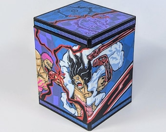 May include: A square box with a blue and purple design featuring anime characters. The box has a black border with a Greek key pattern. The top of the box has a blue and purple design. The sides of the box feature illustrations of anime characters.