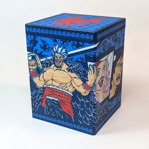 May include: A square blue storage box featuring a graphic illustration of a muscular character with spiky hair, a red belt, and a dark cape. The side panels display additional character portraits, while the lid shows a red skull emblem.