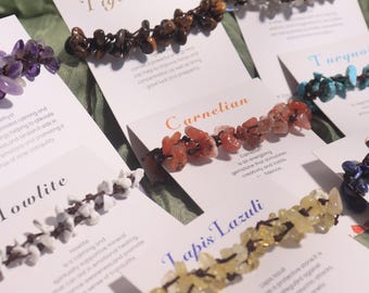 May include: Assortment of gemstone bracelets displayed on cards. The bracelets feature various stones like tiger eye, carnelian, and lapis lazuli, each with a unique color and texture. The cards provide information about each stone.