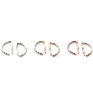 May include: Three pairs of minimalist half-circle earrings in silver, gold, and rose gold. Each earring features a curved half-circle design with a straight bar extending from the flat edge. The earrings are displayed on a white background.