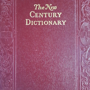 May include: A maroon-colored book titled "The New Century Dictionary." The cover has a textured surface and ornate gold-colored decorative borders and accents. The title is in gold lettering.