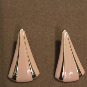May include: A pair of vintage earrings with a geometric design. Each earring is a light pink color with silver-colored metal accents. The earrings have a triangular shape with a flared base and a pointed top.