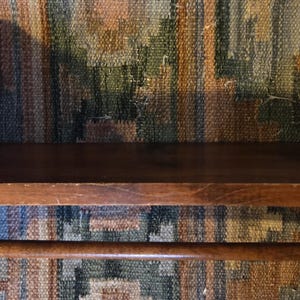 May include: A wooden shelf with a dark brown finish. The shelf has a flat top and a lower rod. The sides of the shelf have a curved design. The shelf is made of wood and is designed to be mounted on a wall.