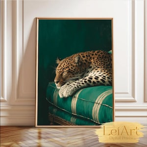 Op de afbeelding: Een ingelijste print van een slapende luipaard op een groen gestreept kussen. De vacht van de luipaard is gevlekt. De achtergrond is donkergroen en de print zit in een goudkleurige lijst. De afbeelding is gelabeld "LeiArt Digital Prints."