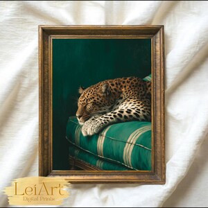 May include: A framed print featuring a sleeping leopard resting on a green striped cushion. The artwork has a dark green background and is enclosed in a gold-colored frame. The print is labeled "LeiArt Digital Prints".
