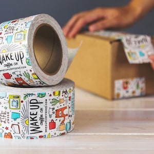 May include: Two rolls of white packing tape with a colorful design featuring the text "Wake Up Coffee Co." and various illustrations of coffee cups, mugs, and other coffee-related items.