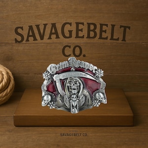 May include: A silver belt buckle with a red enamel background featuring a Grim Reaper design. The buckle says "Grim Reaper" and "Memento Mori" and is made by Savagebelt Co.