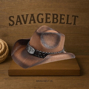 May include: A brown cowboy hat with a distressed finish and a silver buckle with a design. The hat is on a wooden surface with the text "SAVAGEBELT CO." below it.