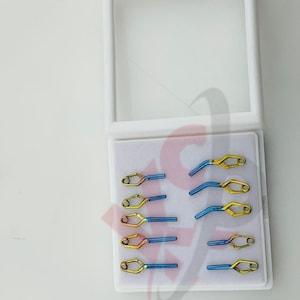 May include: A set of surgical instruments in a white case. The instruments are a combination of gold and blue, with a unique curved design. The case has a clear lid and the brand name "Kynea" is visible.