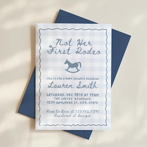May include: A baby sprinkle invitation with a blue gingham pattern and the text "Not Her First Rodeo." The invitation includes details for Lauren Smith's baby sprinkle, with a rocking horse graphic. The invitation is on a white surface with a blue envelope.