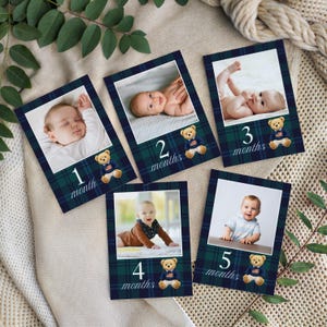 May include: Set of five baby milestone cards. Each card features a photo of a baby and a number indicating the month. The cards have a navy blue and green plaid border, a teddy bear graphic, and the word "month".