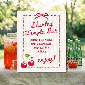 Può includere: Un cartello per un bar Shirley Temple con testo rosso e un bordo decorativo. Il cartello include istruzioni e un'illustrazione di ciliegie. Un grande distributore di bevande in vetro e bottiglie di ginger ale sono visibili.