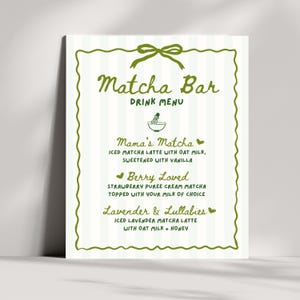 May include: A white Matcha Bar drink menu with green accents. The menu features a green bow at the top and a decorative green border. The menu lists three matcha latte options: Mama's Matcha, Berry Loved, and Lavender & Lullabies.