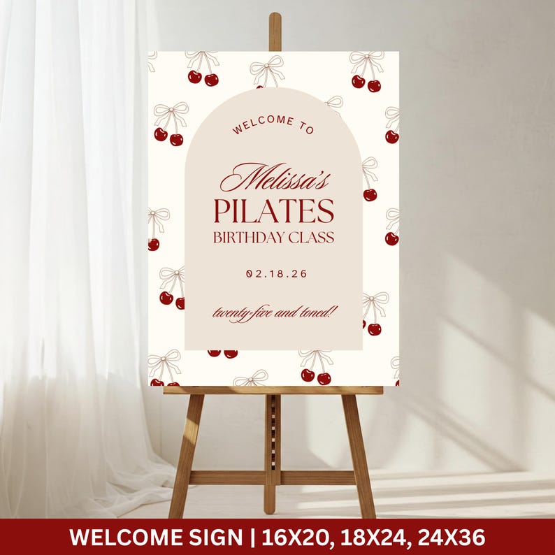 May include: A welcome sign on an easel with the text "Welcome to Melissa's Pilates Birthday Class" in burgundy script. The background is cream-colored with a pattern of cherries and bows. The sign also includes the date 02.18.26 and the phrase "twenty-five and toned!"