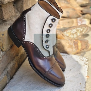 Puede incluir: Botas de cuero marrón con una parte superior de lona blanca y cierres de botón negros. Las botas tienen un diseño de punta de ala y un detalle de brogue.