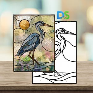 May include: Stained glass panel featuring a blue heron standing in water, with a golden sun in the background. The artwork is framed in a dark brown border. A black and white line drawing of the heron is next to the panel.
