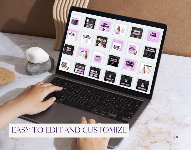 May include: A laptop displaying a presentation with pink and black slides. The text "EASY TO EDIT AND CUSTOMIZE" is at the bottom of the screen. The laptop is on a marble surface with decorative stones and a wooden accent in the background.