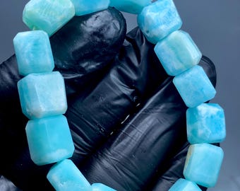 Può includere: Un braccialetto realizzato con perline di amazonite di forma quadrata e lucidate di colore blu chiaro.