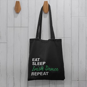 May include: Black tote bag with white text that reads "Eat Sleep Irish Dance Repeat" in green lettering.