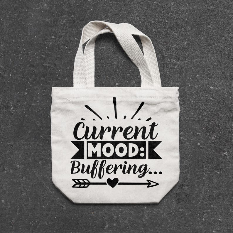 May include: A small, off-white canvas tote bag with a black graphic that reads "Current MOOD: Buffering...". The design includes an arrow, heart, and decorative lines. The bag has two short handles.